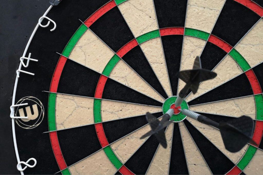 Close-up of a dartboard with three darts in the board's bullseye.